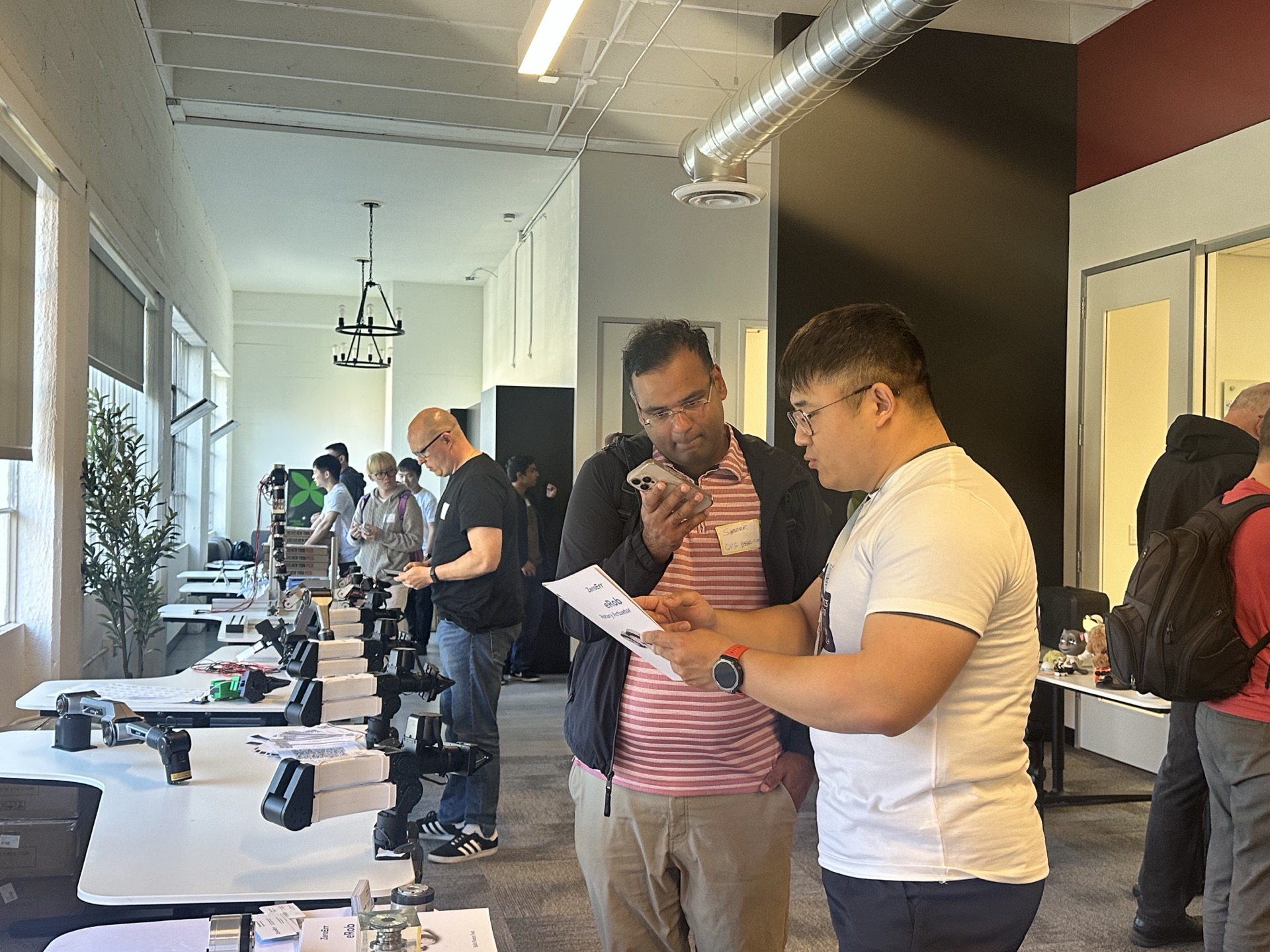 Attendees examining robotic arm components and hardware at SVRC May 2026 demo tables