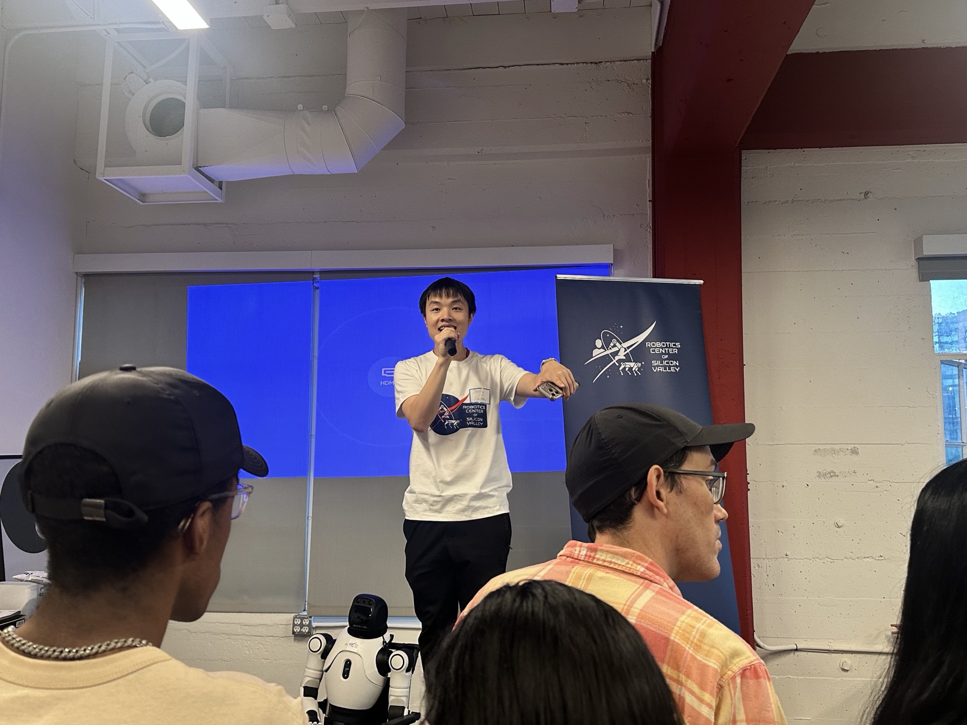 Speaker presenting at SVRC May 8 meetup with humanoid robot visible on stage